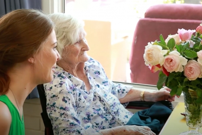 Elderly woman and female carer looking at a floral arrangement