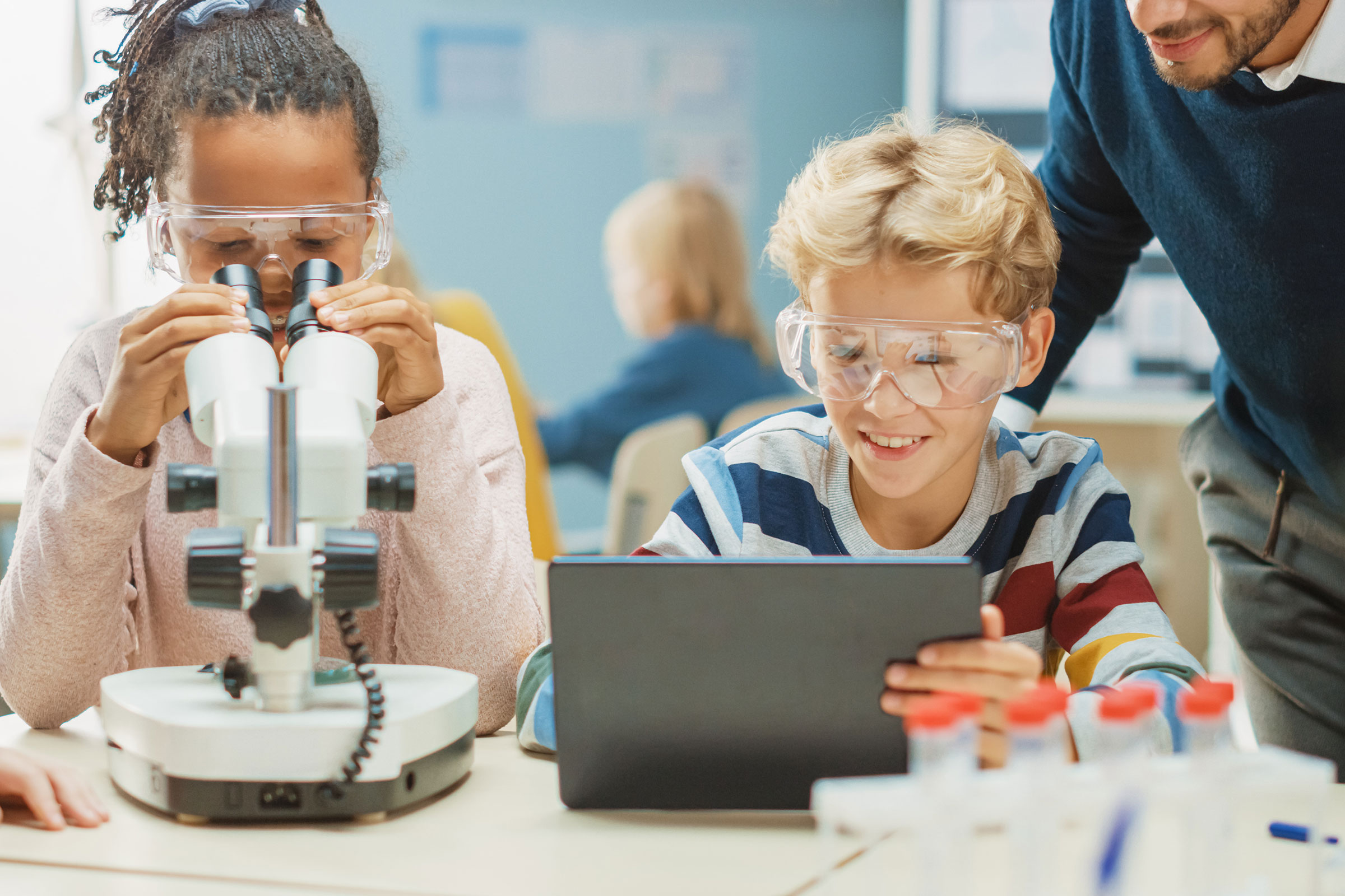 Science lesson: children using microscope and computer tablet
