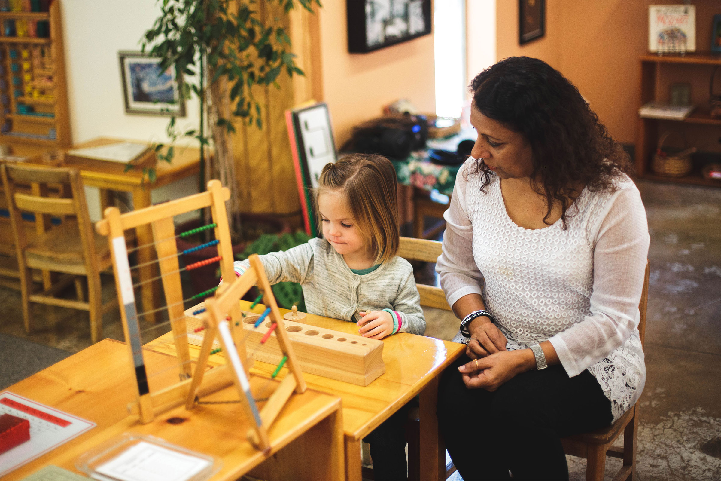 Directress watches child using Montessori materials