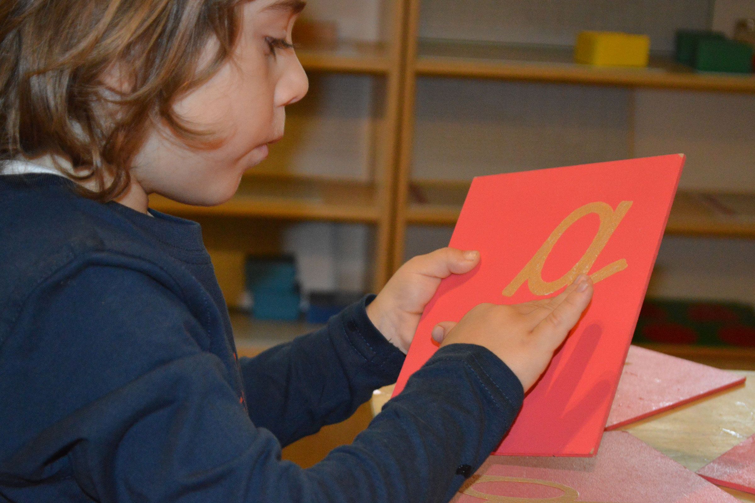 Child tracing Montessori sandpaper letter material